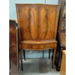 A reproduction mahogany bow fronted drinks cabinet with double doors & double drawers, on tapered