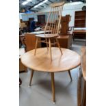 An Ercol light oak dining suite comprising table with circular drop leaf top and 4 stick back chairs