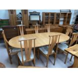 An Ercol light elm dining suite comprising extending 'D' end table on trestle base, extended