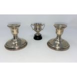 A pair of sterling silver candlesticks; a hallmarked silver small trophy cup, 1 oz