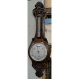 An Edwardian aneroid barometer in carved oak case