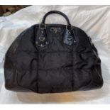 A Prada black quilted nylon small hold all bag with twin rolled handles and shoulder strap, silver