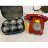 A 1970's red vintage telephone; a set of boules