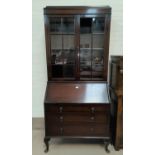 A 1930's oak bureau/bookcase with twin glazed doors over fall front and 3 drawers, on cabriole