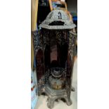 A 19th century hexagonal cathedral heater in pierced cast iron with red glass panels and oil