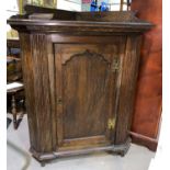 A late Georgian style oak corner cupboard, floor standing with single ogee panelled door, width 87