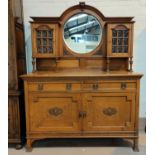 A late Arts & Crafts golden oak sideboard of 2 cupboards with convex glass panels, and circular