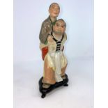 A Chinese ceramic group , son carrying mother on his back (some areas of damage) on wooden stand (