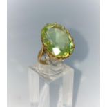A yellow metal dress ring set with large oval citrine / peridot type stone, shank unmarked tests