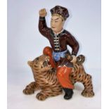 A Chinese ceramic figure of man seated on a tiger holding its tail, unmarked, height 21.5cm