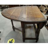 An oak dining table with oval carved drop leaf top, on barley twist legs
