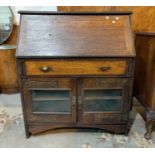 An early 20th century Arts and Crafts oak bureau with glazed doors below, 95 cm