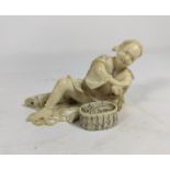 A late 19th/early 20th Century Japanese ivory Okimono depicting a man reclining coiling rope,
