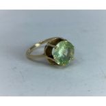 A yellow metal dress ring with citrine / peridot type stone in raised setting, tests as 9 ct, size N
