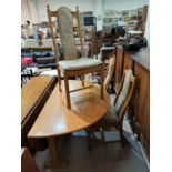 A modern Ercol light oak dining table with drop leaf and 4 chairs with carved wheat pattern