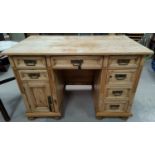 A 19th century stripped pine kneehole desk with 7 drawers and cupboard