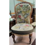 A Victorian carved walnut nursing chair with spoon back, in hand worked needlework fabric