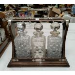 A stained wood 3 bottle tantalus with silver plated mounts (no key)