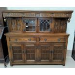 A reproduction oak large buffet/sideboard, heavily carved, with glazed cupboard over 2 drawers and