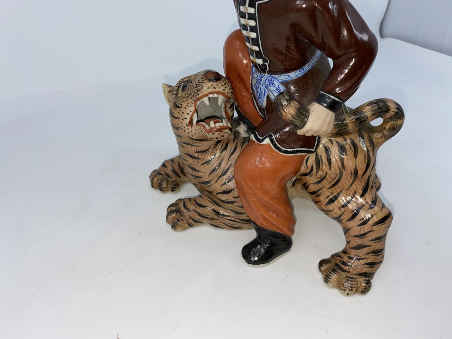 A Chinese ceramic figure of man seated on a tiger holding its tail, unmarked, height 21.5cm - Image 2 of 5