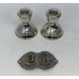 A hallmarked silver pair of dwarf candlesticks; a nurse's silver plated buckle with Egyptian