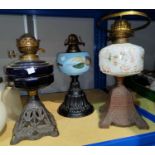 Three Victorian cast iron oil lamps with coloured glass
