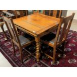 A golden oak draw leaf dining table on barley twist legs with x-frame stretcher to base and a set of