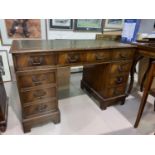 A figured mahogany period style kneehole desk with 9 drawers and inset leather top