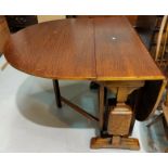 A 1930's golden oak drop leaf dining table on carved square legs
