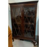 A 1920's mahogany Georgian style display cabinet enclosed by astragal glazed doors, on short