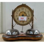 A brass alarm clock of unusual cylindrical form with 2 bells under, on wooden plinth