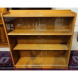 A 1930's oak bookcase enclosed by 2 pairs of glass sliding doors