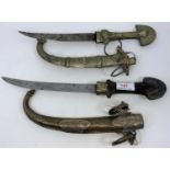 Two Middle Eastern ornamental daggers with curved blades in ornate silver chased metal scabbards, 40