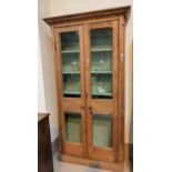 A full height bookcase in antique natural pine, enclosed by twin glazed doors, 100 cm