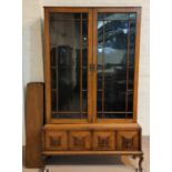 An early 20th century golden oak side cabinet enclosed by 2 glazed doors over 2 drawers, on cabriole