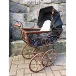 An early 20th century doll's pram with black linen concertina sun canopy, of wicker and metal