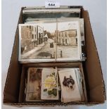 A collection of early 20th century postcards with a box of cigarette cards