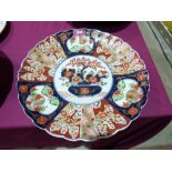 A Japanese Imari charger with scalloped rim, typically decorated with a vase of flowers to the