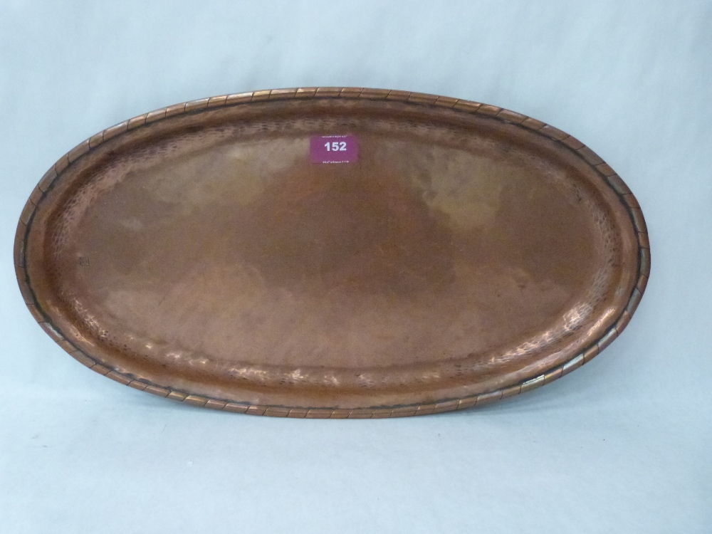 A Hugh Walker copper planished copper oval salver, the fold-over rim with traces of silvering.