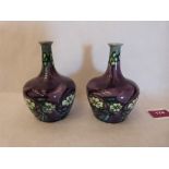 A pair of Minton Secessionist vases, number 33, tube-line decorated with flowers on a purple ground.
