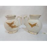 A pair of Brownfield + Son salt glazed jugs decorated with gilded cranes on a stippled ground.