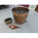 A copper log bin on brass paw feet, 22½' diam; a small brass jardiniere (A.F.) a poker, bellows
