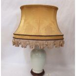 A Chinese design celadon glazed table with yellow silk shade, raised on a pierced wood base. The