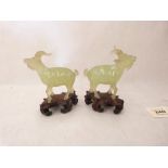 A pair of Chinese carved jade rams on hardwood bases. The figures 3¾' high. Damage and repairs