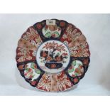 A Japanese Imari charger with scalloped rim, typically decorated with a vase of flowers to the
