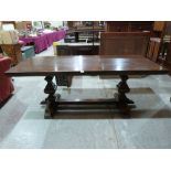 An oak refectory dining table raised on truncated supports united by a pegged stretcher. 79' long