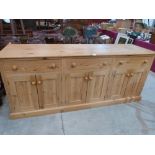 A pine dresser base with three frieze drawers over three pairs of cupboard doors. 84' wide