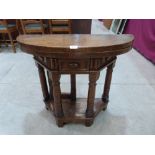 An antique semi-circular oak folding (credence) table, the panelled frieze with a drawer, raised