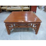 A Chinese lacquered low table with geometrically fret carved sides, on square legs. 38' wide