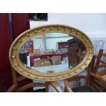 A 19th century gilt oval wall mirror with ball applied frame and bevelled plate. 39' wide